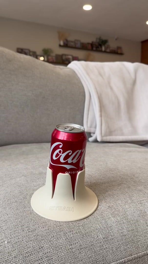 The demo: a full tumbler steady in the holder on a couch cushion as someone sits down beside it.